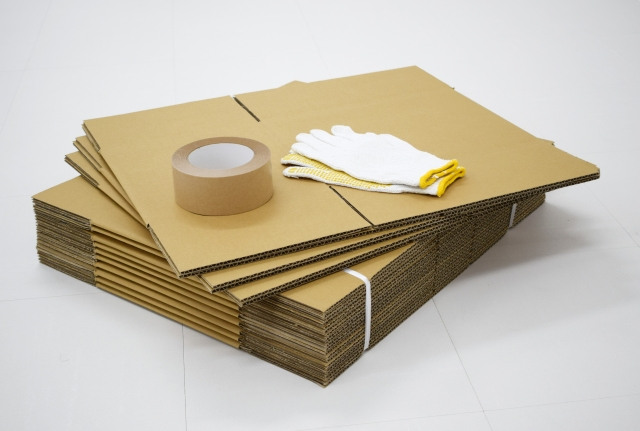 梱包された新品の段ボールの上に置かれた軍手と布テープ